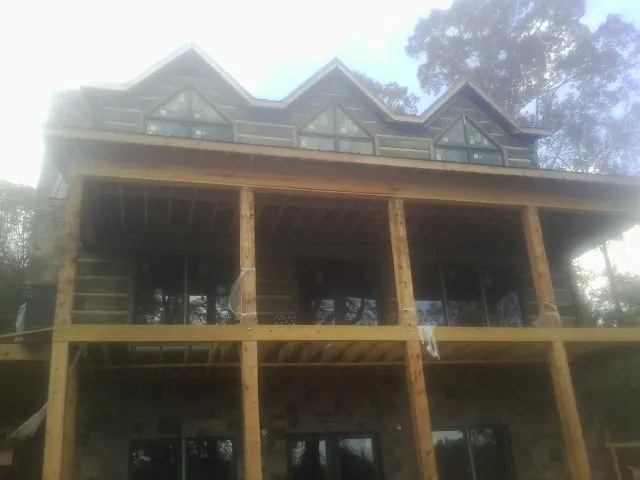 Dormers and porch framing on a large log home under construction — Roof Coating work by our crew in Bloomingdale