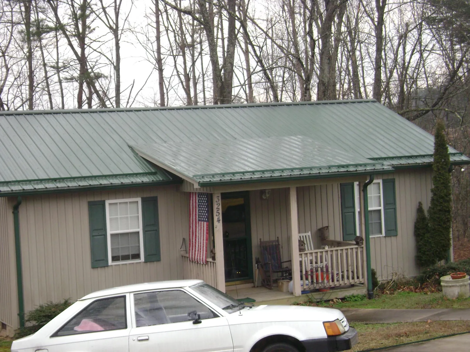 Green metal roof and front porch on a tan sided cottage in Bloomingdale