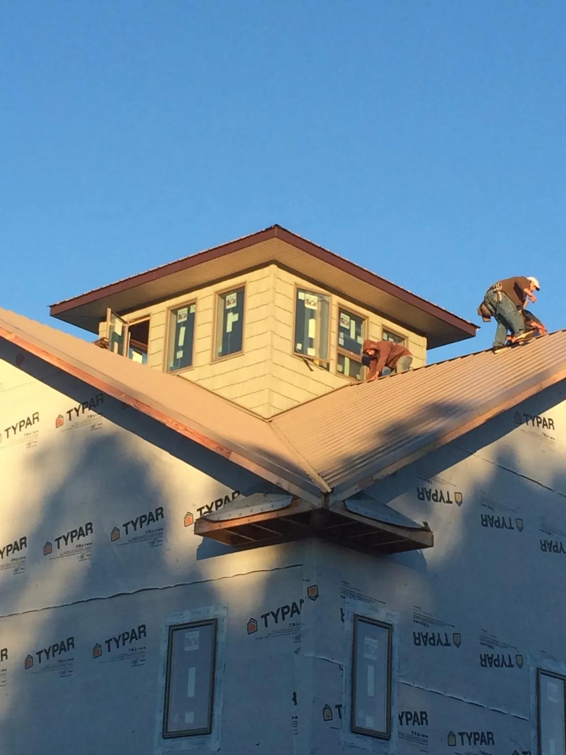 Roofers working around a rooftop cupola on a new metal roof at sunset — Roof Waterproofing in Bloomingdale by Roofing Brothers